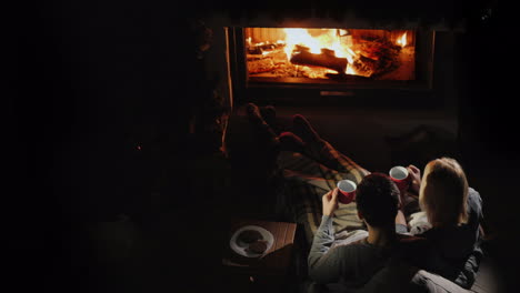 man and woman drink tea by the fireplace good evening together home comfort