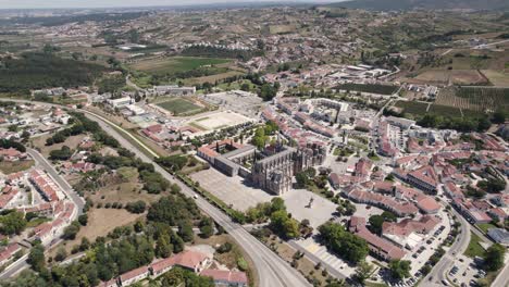 Vista-Panorámica-Aérea-Del-Monasterio-De-Batalha,-La-Ciudad-Circundante-Y-La-Autopista-Ic2