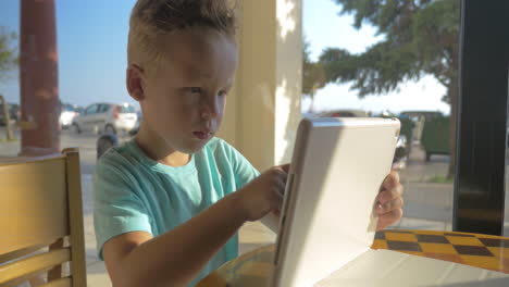 child playing with pad in street cafe