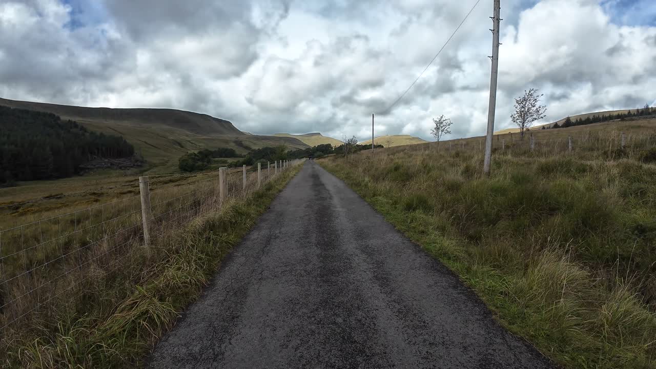 Sunlit forest path with wooden footbridge, alongside serene creek in lush greenery of Brecon Beacons National Park. Nature’s tranquility captured in vibrant detail, no people present