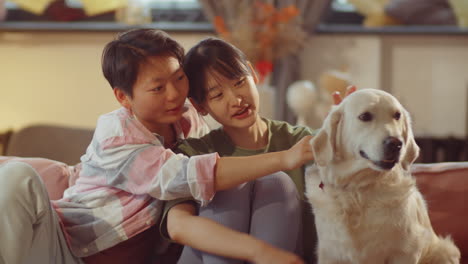 asian lesbian couple petting dog at home