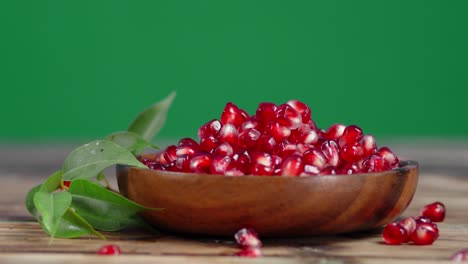 grains of fresh pomegranate on wooden bowl rotate slowly.
