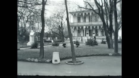 man walking down sidewalk in black and white video. circa ussr 1970: a black and white video capturing a man walking down a sidewalk, revealing a glimpse of life in the soviet union.