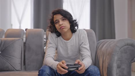 bored indian kid boy playing video games on controller