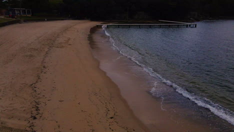 Waves-lapping-a-beach-drone-flight-over-seagulls