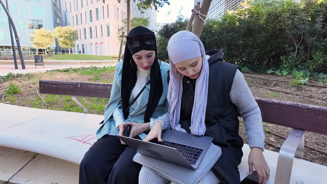 Two women with hijabs using a laptop in a park | Premium Stock Video ...