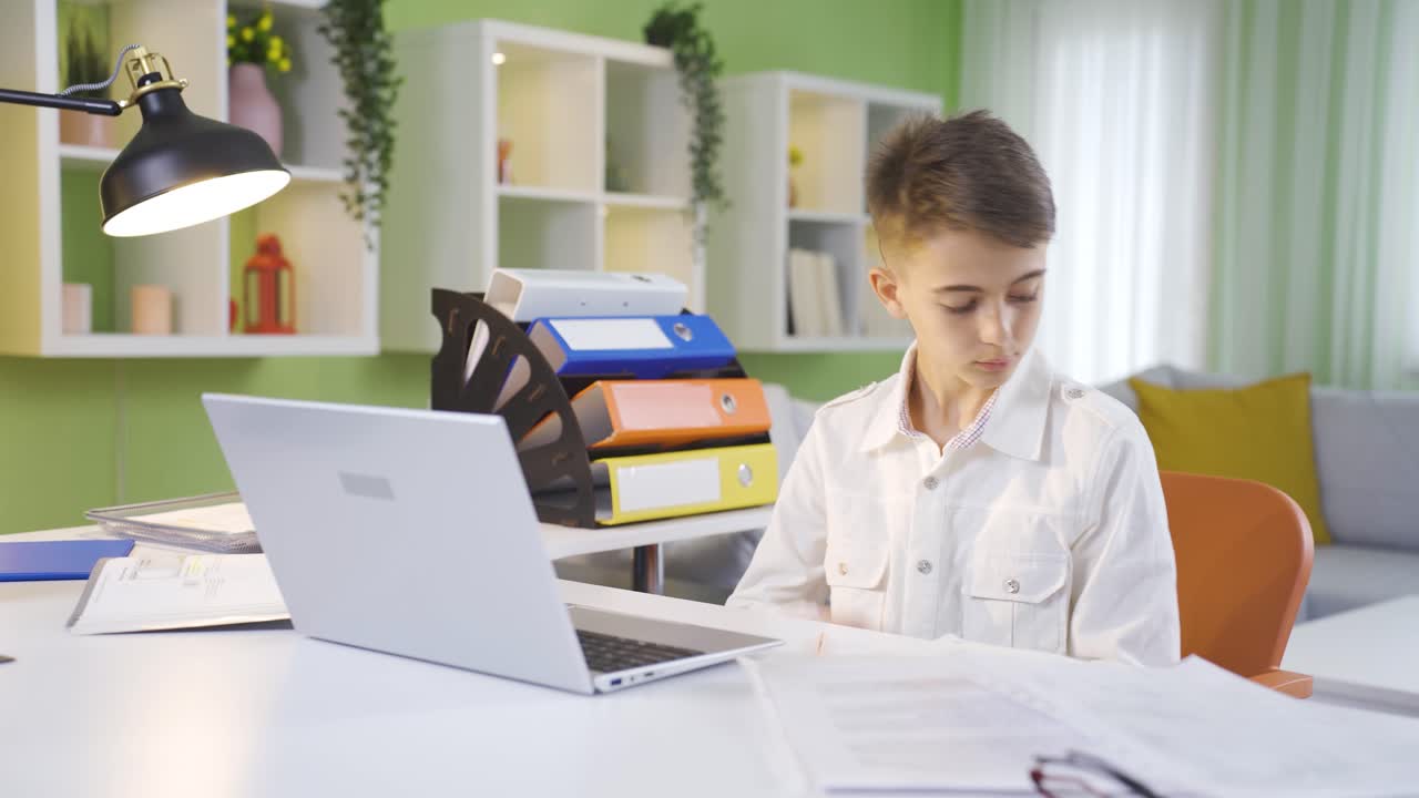 Boy dreaming of being a businessman in his father's home office. Curious boy.