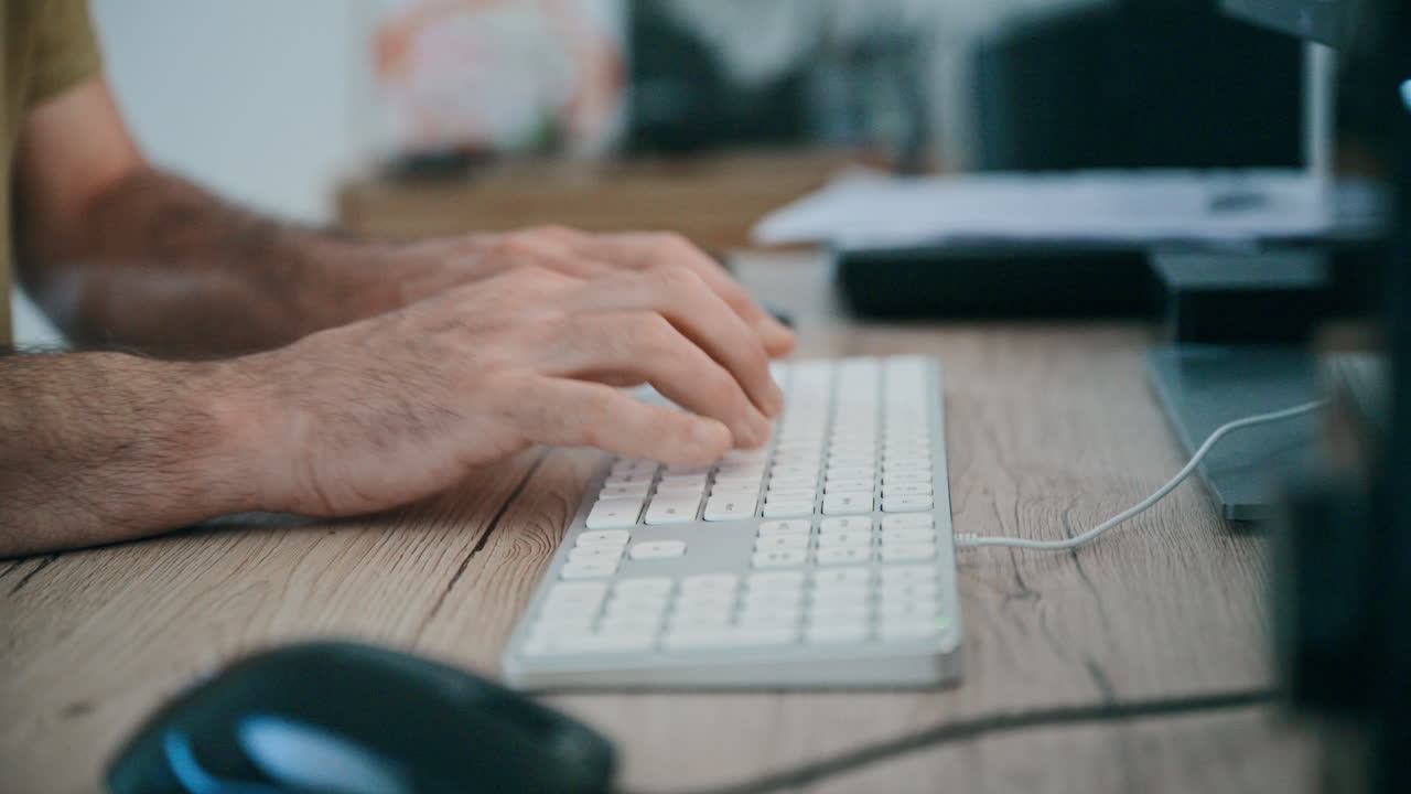 Hands typing on computer keyboard at wooden desk — office work and remote productivity scene, 4K