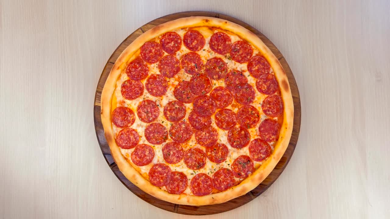 테이블 위에 있는 나무판 위의 살라미 피자.