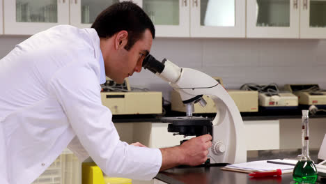 Joven-Científico-Mirando-A-Través-Del-Microscopio-En-El-Laboratorio