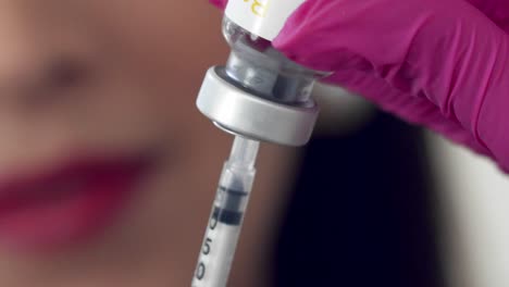 filling a syringe with clear medication for an injection - close up