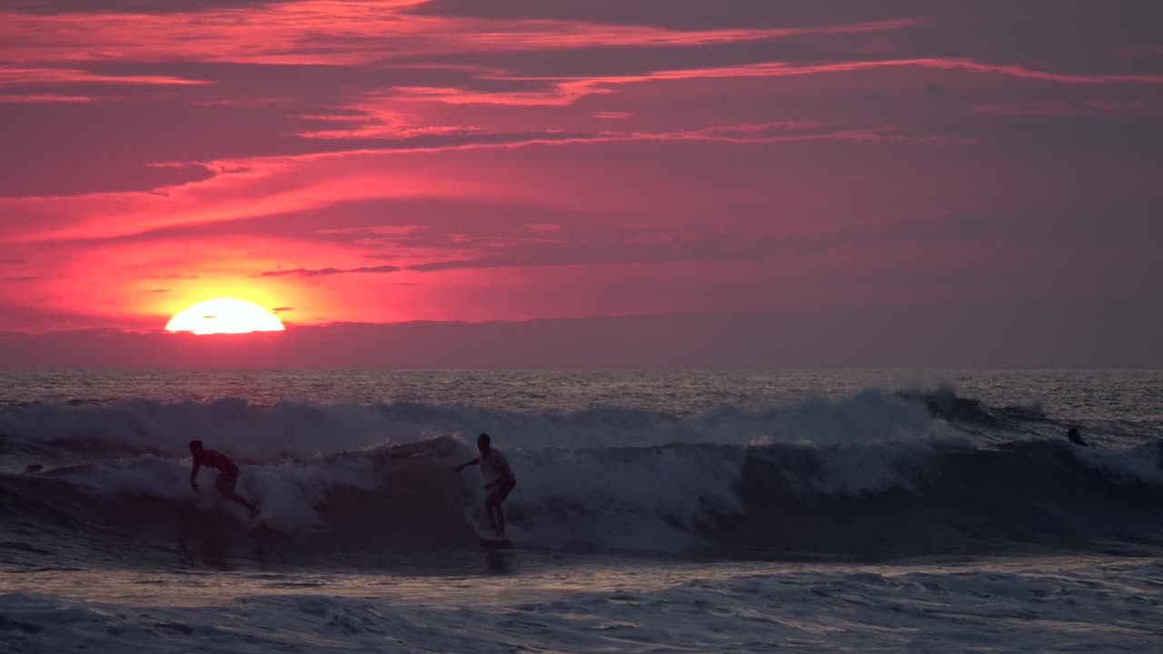 Surfers Silhouetted Against a Vibrant Sunset