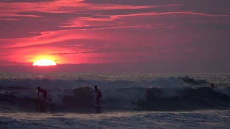 surfers silhouetted against a vibrant sunset