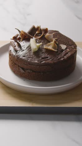 Vertical-Video-Of-Homemade-Chocolate-Cake-On-Plate-On-Kitchen-Work-Surface-Dusted-With-Icing-Sugar