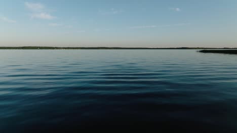 push in aerial drone shot directly over a large lake at sunset