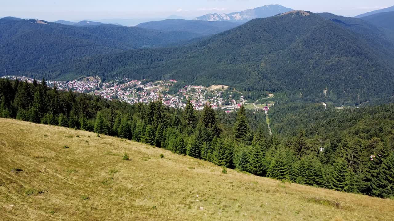 imágenes aéreas sobre un bosque con un pueblo de montaña al fondo