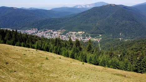 aerial footage over a forest with a mountain village in the background