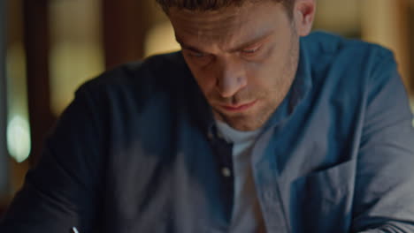 Guy arms writing pen at evening workplace closeup. Focused man making notes
