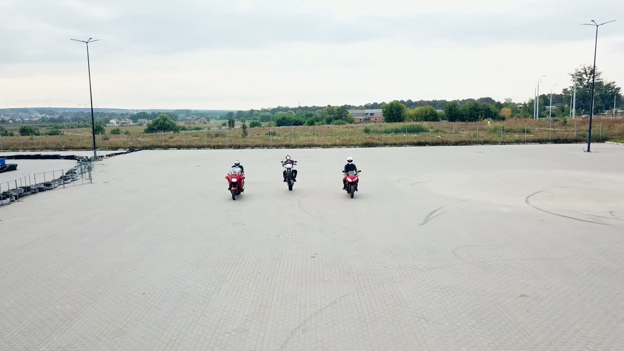 Motorcycling racing outdoors. Three motorbikers started racing and one of the bikers on a high speed moves first ahead.