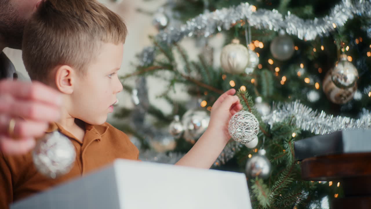 작은 소년이 아빠가 크리스마스 트리를 장식하는 데 도움을 주고 있다