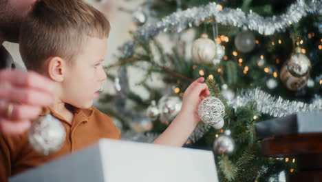 niño pequeño ayudando a papá a decorar el árbol de navidad