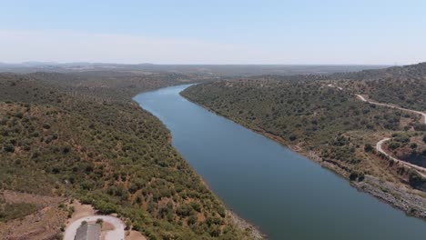 flying up the expansive guadiana river passing above alqueva dam structures