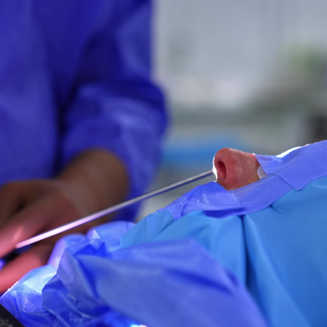 Surgeon's hands holding an instrument with light on its top. Doctor is ready to use the tool at operation. Close up