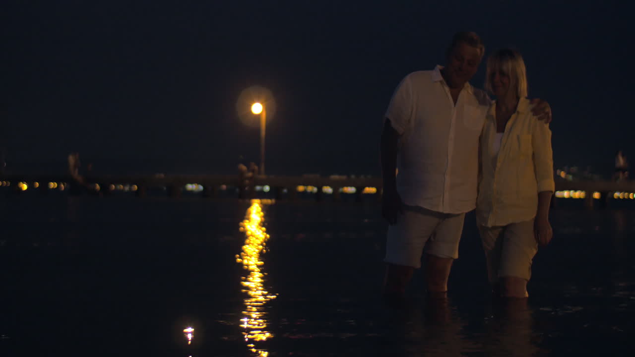 커플 이 물 위 에 항해 하는 불 을 지켜보고 있다