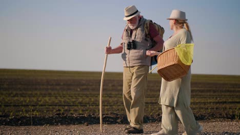 grandparents walk together in nature. going on a picnic. elderly retired couple talking while walking in a field