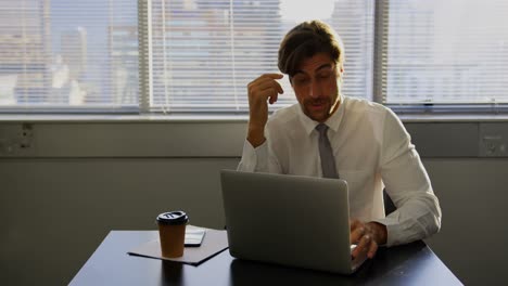 Vista-Frontal-De-Un-Joven-Ejecutivo-Caucásico-Cansado-Trabajando-En-Una-Computadora-Portátil-En-El-Escritorio-En-Una-Oficina-Moderna-4k