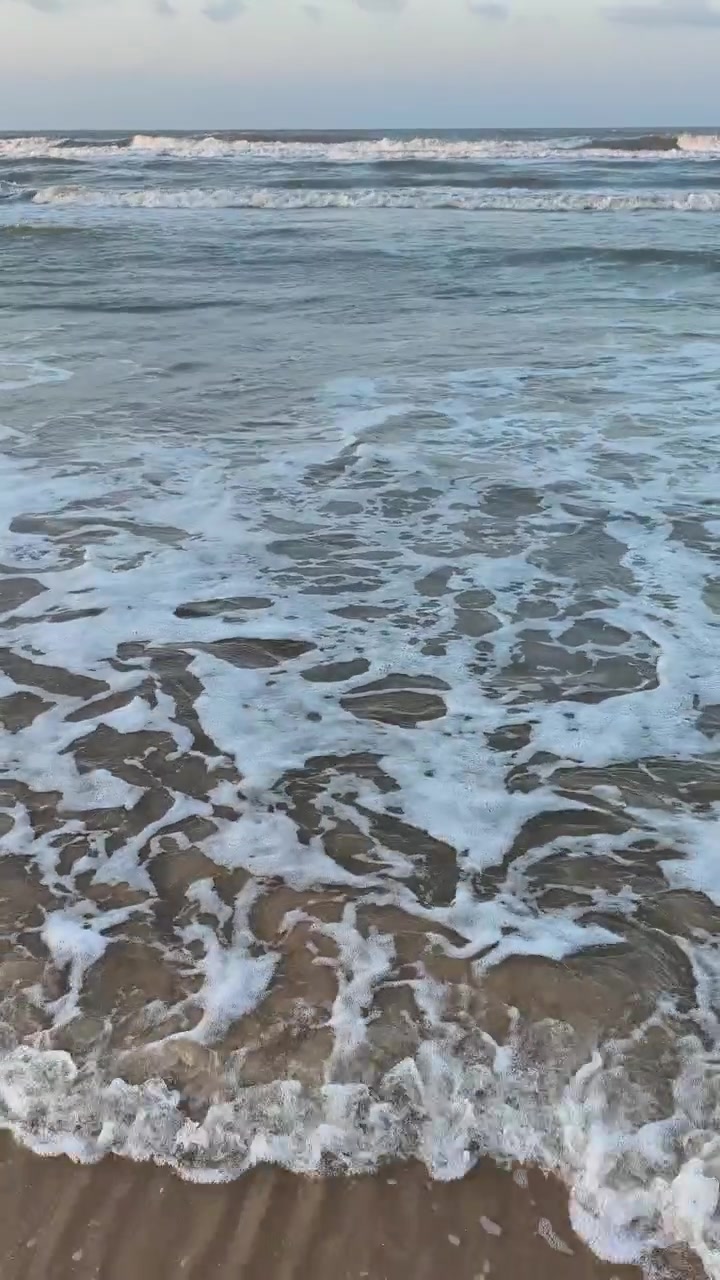 Onde delicate dell'oceano che si infrangono su un litorale sabbioso