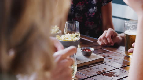 close up of friends eating fries as they meet in restaurant bar