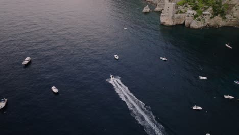 Lancha-Rápida-En-El-Océano-Turquesa-Cerca-Del-Pueblo-Del-Acantilado-De-Positano-En-La-Costa-De-Amalfi,-Campania,-Italia