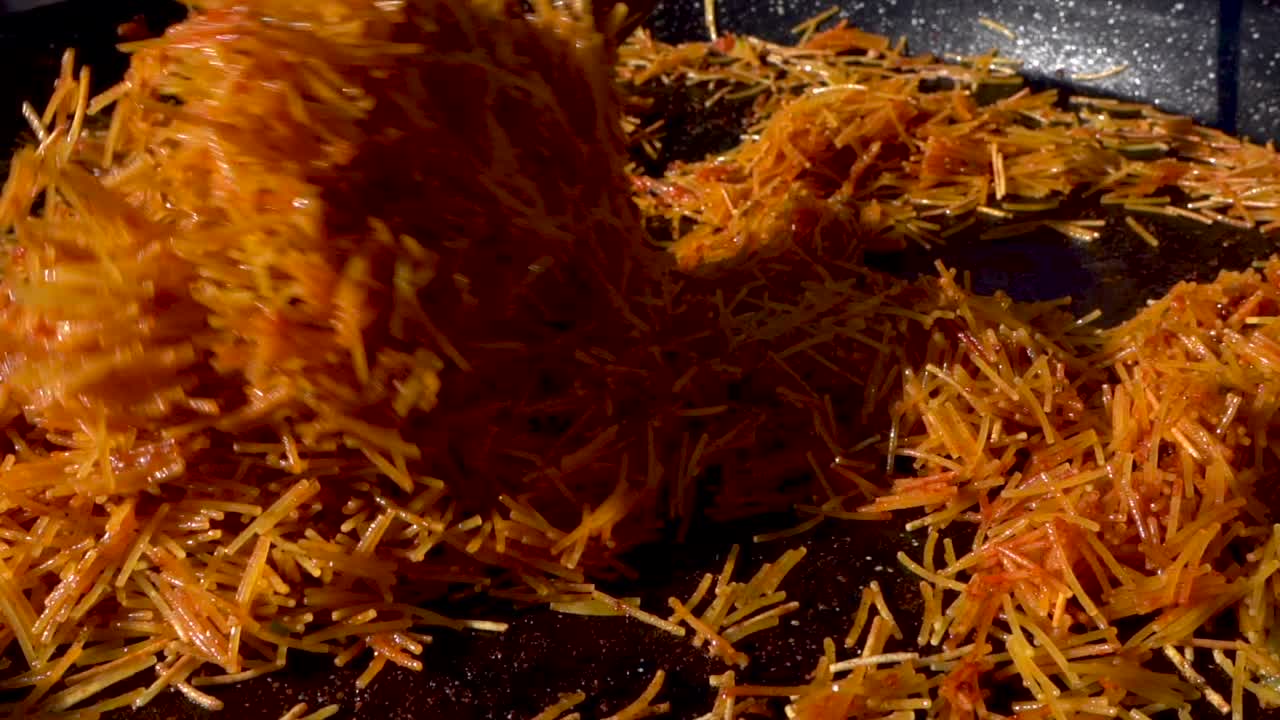 해산물 빠에야를 만들기 위해 약간의 소스로 팬에 파스타를 볶고 저어줍니다