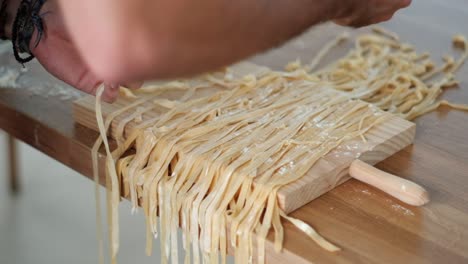 cinematic close-up of chef preventing stickiness - tagliatelle sorting with flour