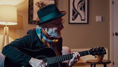 senior man playing acoustic guitar in a cozy living room