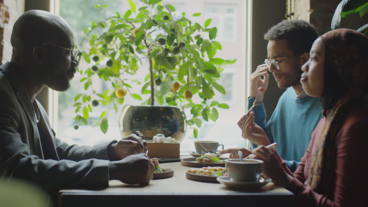 Multiethnic Colleagues Talking over Lunch in Cafe