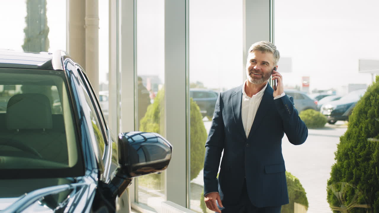 Uomo d'affari che parla al telefono in una concessionaria di auto