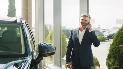 un hombre de negocios hablando por teléfono en un concesionario de coches.