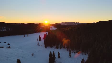 nature captured with a drone with the landscape, mountains covered in snow at golden hour at sunrise with  forest and surrounding hills captured in slovenia above forest pokljuka  above a village