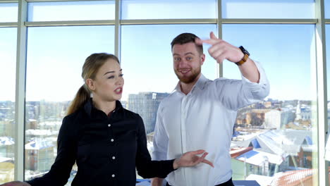 happy young colleagues advertise their company. cheerful girl and handsome guy invite to join to their work gesticulating a lot in office center.