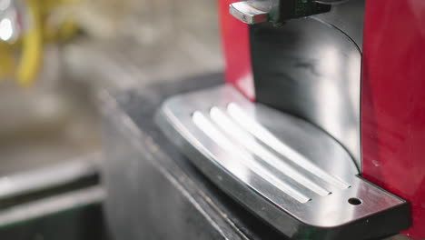 close-up of hand wiping down black surface of red coffee machine with green cloth, focusing on maintaining appliance cleanliness and neatness, showcasing kitchen care and attention to detail