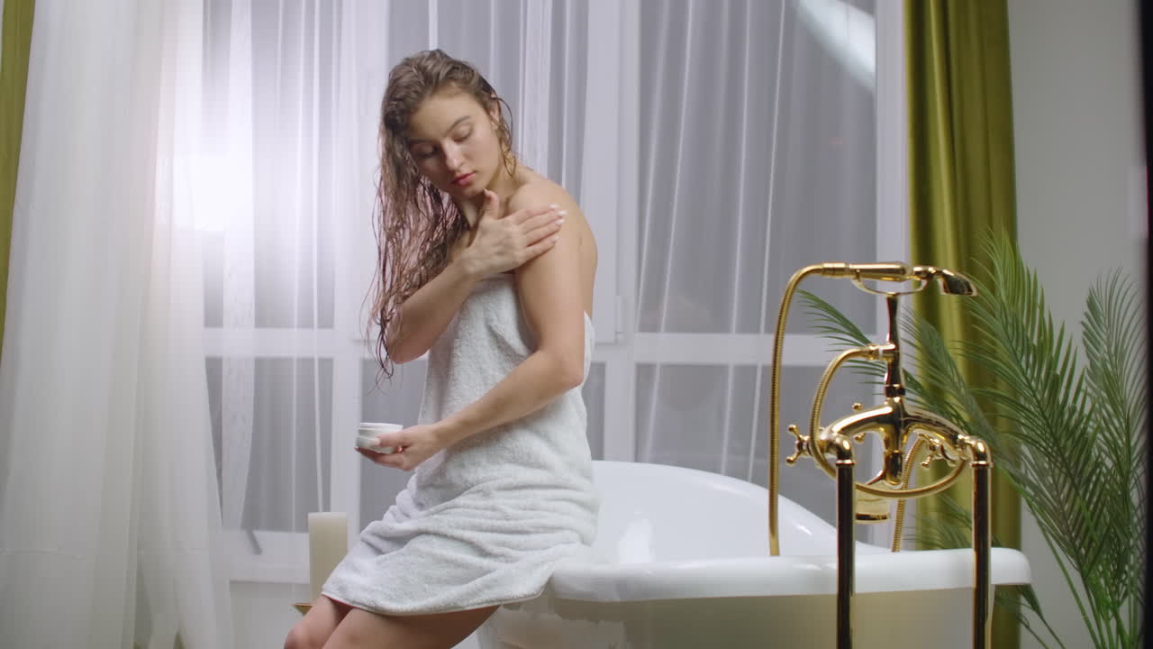 mujer joven aplicando loción corporal por la mañana. primer plano de cuidado corporal de la mujer en el hogar. retrato de mujer aplicando crema hidratante en el cuello. cuidado natural de la piel.