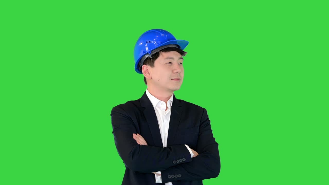 초록색 스크린, 크로마 키에 손을 접고 서 있는 슈트와 하드을 입은 아시아 엔지니어