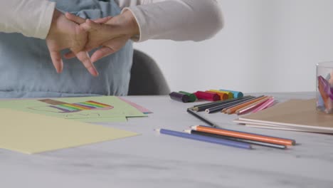 Close-Up-Studio-Shot-Of-Young-Girl-At-Table-Drawing-And-Colouring-In-Picture-