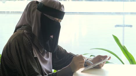 muslim woman using tablet in cafe