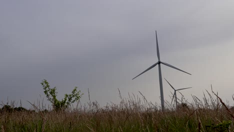 Video-features-Electrical-renewable-energy-wind-turbines-in-Estonia-Harjumaa-Europe-that-are-spinning-in-slow-motion-during-the-summer-time-while-the-sun-is-shining-and-nature-is-around-them