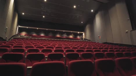 slow dolly shot along rows of red cinema seats with bright lights