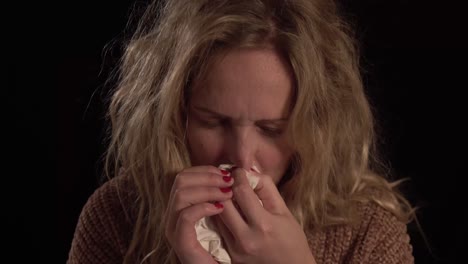 una joven rubia europea se está soplando la nariz.