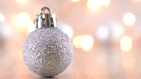 ornamento navideño de brillo plateado con luces parpadeantes detrás